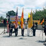 Flags of the two nations that fought side-by-side in the Vietnam War look down upon the dedication of the joint American-Vietnamese Memorial at Les Gove Park on June 16. ROBERT WHALE, Auburn Reporter