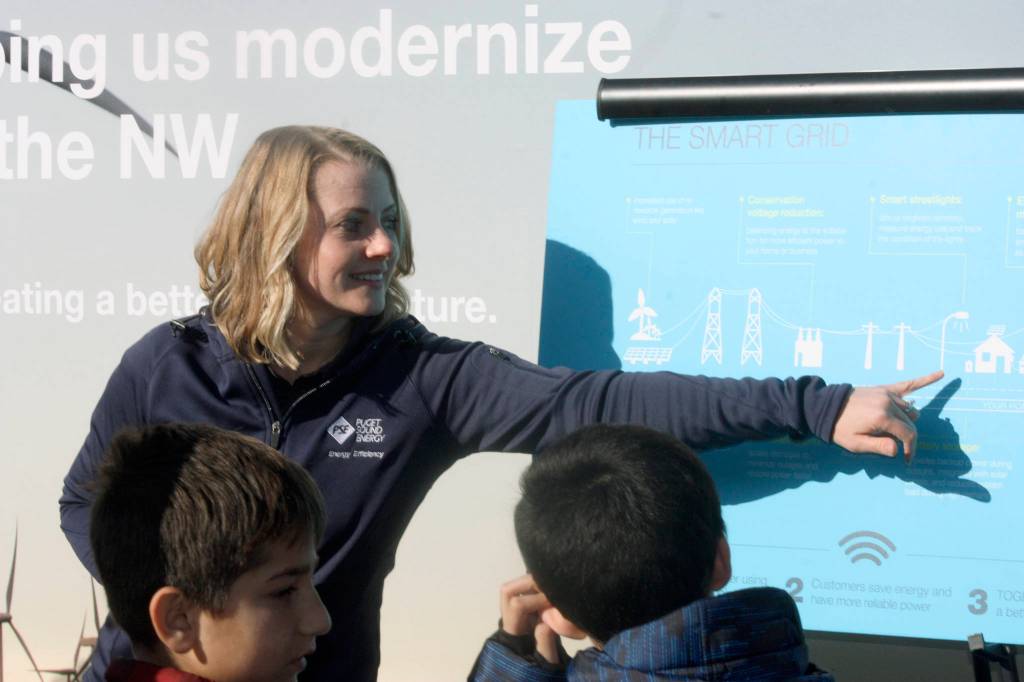 PSE energy efficiency expert Amanda Hoffman shows how the smart grid works in front of PSEs new Electric Grid Trailer, a mobile, interactive vehicle that includes solar panels, a wireless charging station and hands-on activities. PSE visited fifth-graders at Daniel Elementary School on Nov. 8, National STEM Day. MARK KLAAS, Kent Reporter.