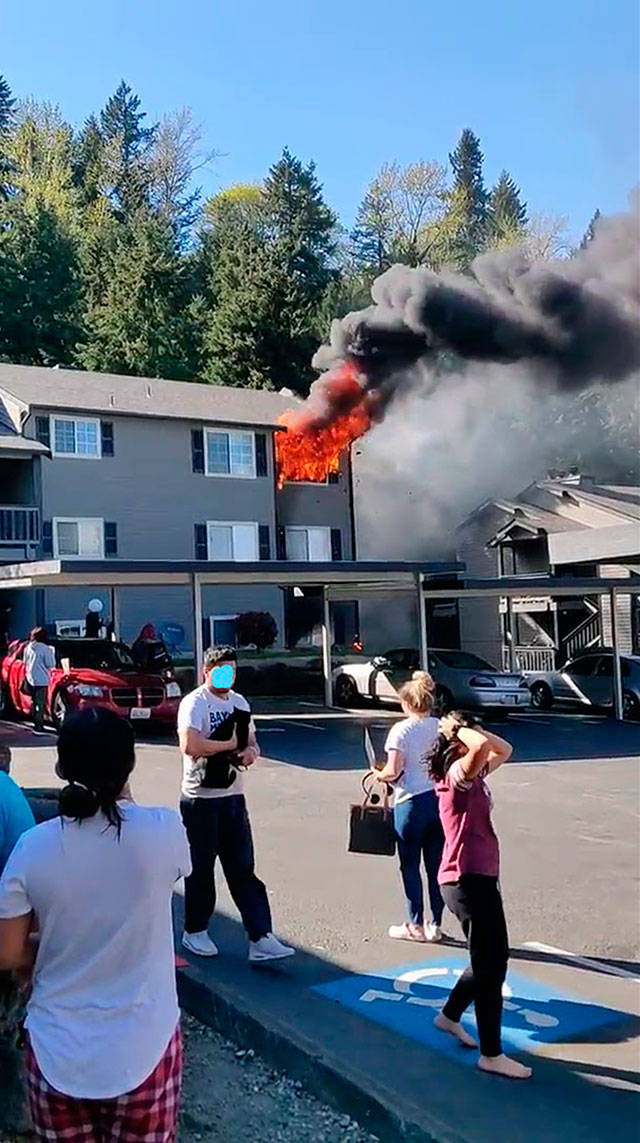 People flee and watch a fire Monday at the Apex West Hill Apartments. A bystander took the photo prior to firefighters arriving. COURTESY PHOTO, Puget Sound Fire