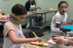 A young chef carefully spreads sauce onto pizza dough during a cooking class at Young Chefs Academy of Covington. Courtesy photo/YCA Covington
