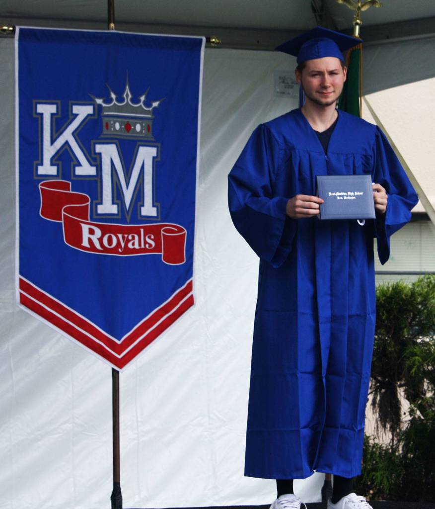 A Kent-Meridian High graduate poses for a photo on a temporary stage in the schools front parking lot. STEVE HUNTER, Kent Reporter