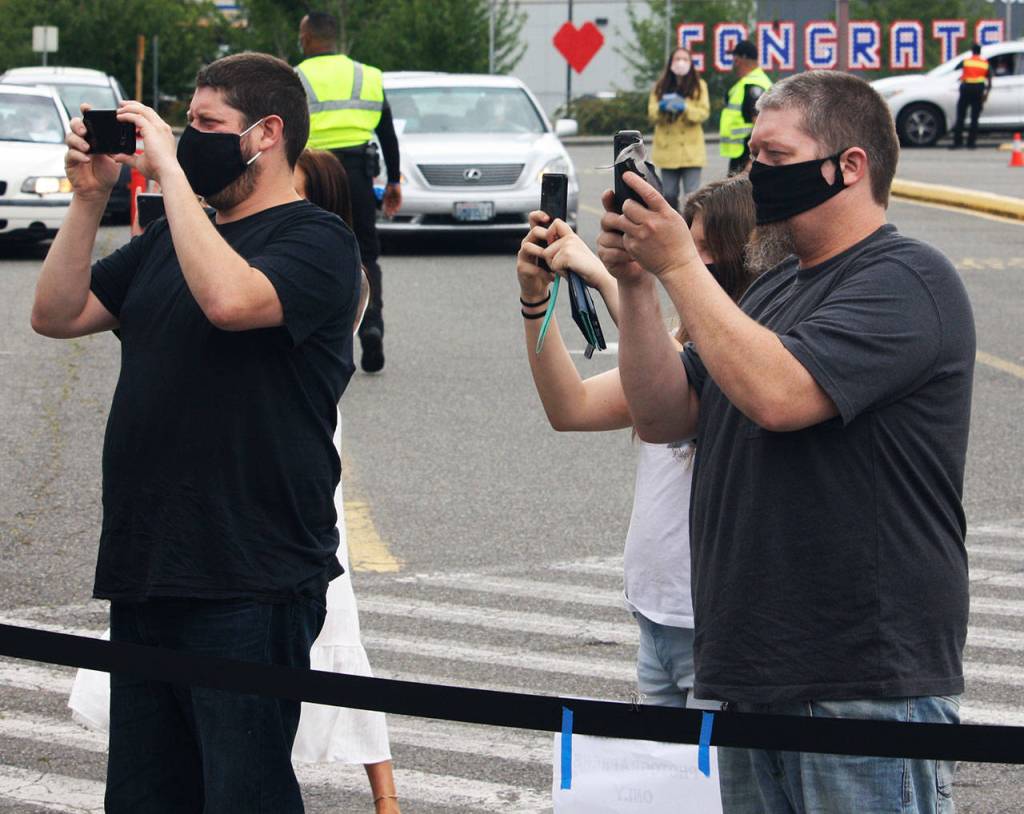 Family members take a photo of a Kent-Meridian graduate from a roped off area in the front parking lot. STEVE HUNTER, Kent Reporter