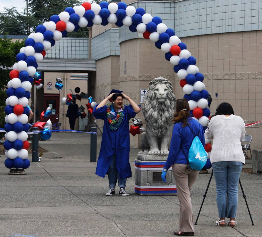 A graduate prepares to pose for a photo next to the Kent-Meridian lion statue. STEVE HUNTER, Kent Reporter