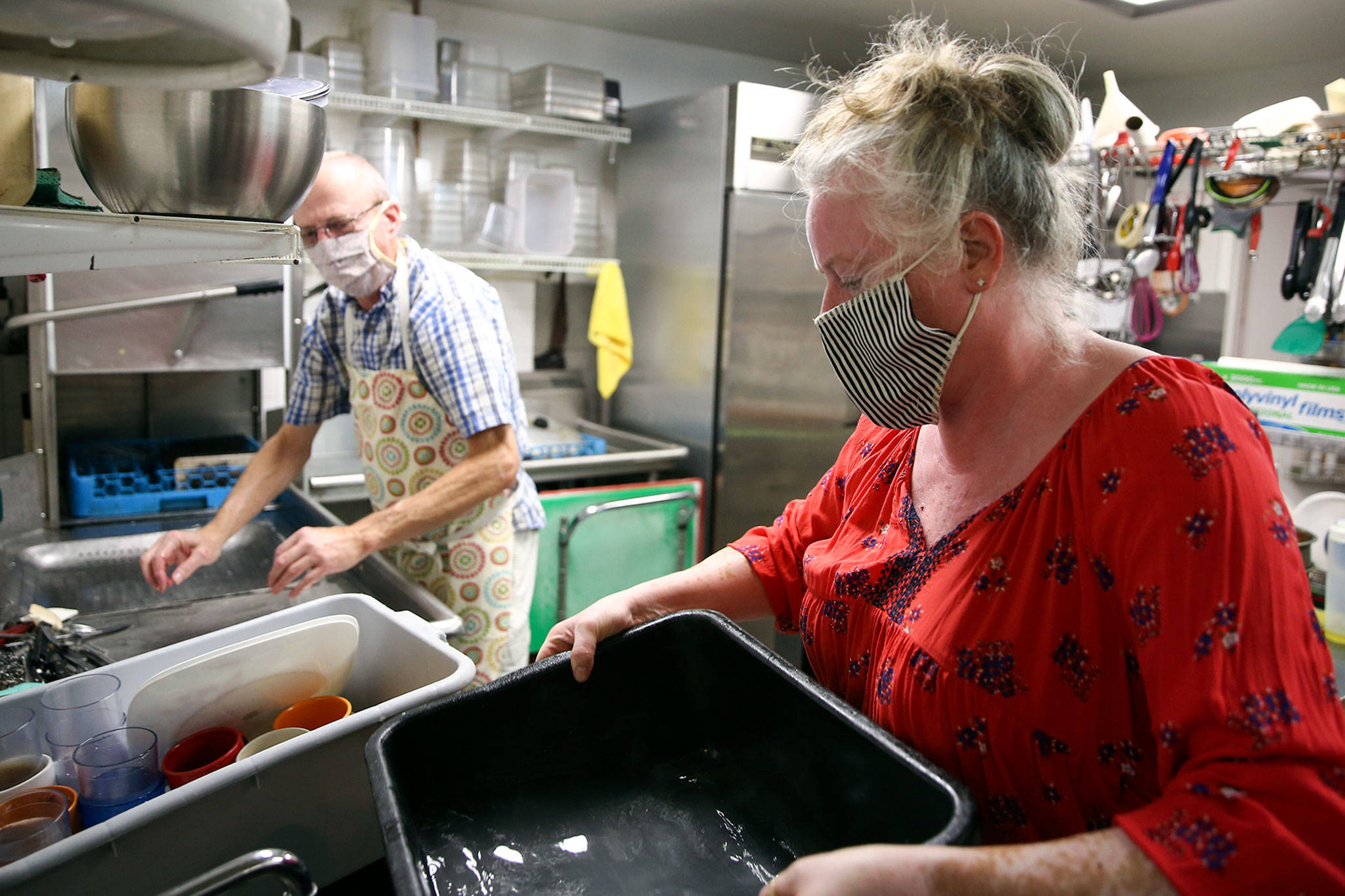 Brian Tilley (left) and Katie Dearman work the wash station Friday at Kates Greek American Deli in Everett. (Kevin Clark / The Herald)
