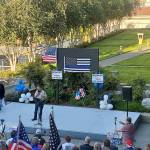 The man who was later arrested can be seen during the rally, behind the stage, holding up his skateboard in the sun. (Ian Davis-Leonard / The Herald)