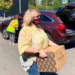 Kent Mayor Dana Ralph delivers a box of food during a free distribution of food, face masks and hand sanitizers on Aug. 28 at the accesso ShoWare Center. COURTESY PHOTO, City of Kent