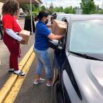 Volunteers deliver a food box to a vehicle during a Kent School District distribution day. COURTESY PHOTO, Kent School District