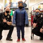 Two Kent Police officers pose with a child during the annual Shop with a Cop on Dec. 19 at the Kent Target store. COURTESY PHOTO, Kent Police