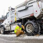 A crew member checks the chains on a snowplow. COURTESY PHOTO, City of Kent