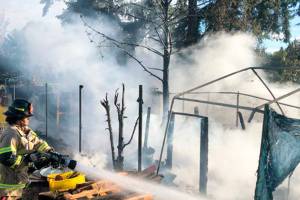 A firefighter battles a blaze at a homeless encampment Sept. 4 in the 24300 block of Pacific Highway South in Kent. COURTESY PHOTO, Puget Sound Fire