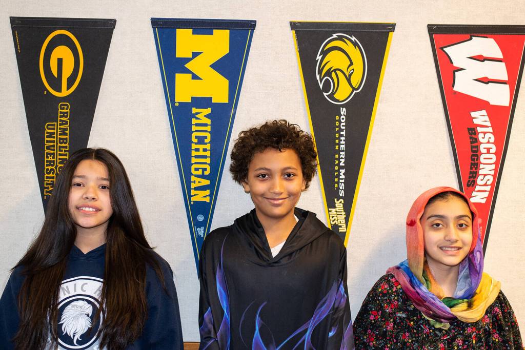 Students Amaia Castellanos Munoz, Jacob Smith and Tabassom Akakhil stand near several of the college pennants displayed at Scenic Hill Elementary. COURTESY PHOTO, Martin Avila