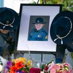 Two troopers place a photo of slain Washington State Patrol trooper Chris Gadd outside WSP District 7 Headquarters about twelve hours after Gadd was struck and killed in a collision on southbound I-5 about a mile from the headquarters on Saturday, March 2, 2024, in Marysville, Washington. (Ryan Berry / The Herald)