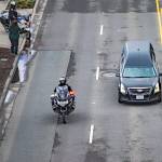 People stand along Marine View Drive and watch as the hearse carrying Washington State Trooper Christopher Gadd drives by in a memorial procession on Tuesday, March 12, 2024 in Everett, Washington. (Olivia Vanni / The Herald)