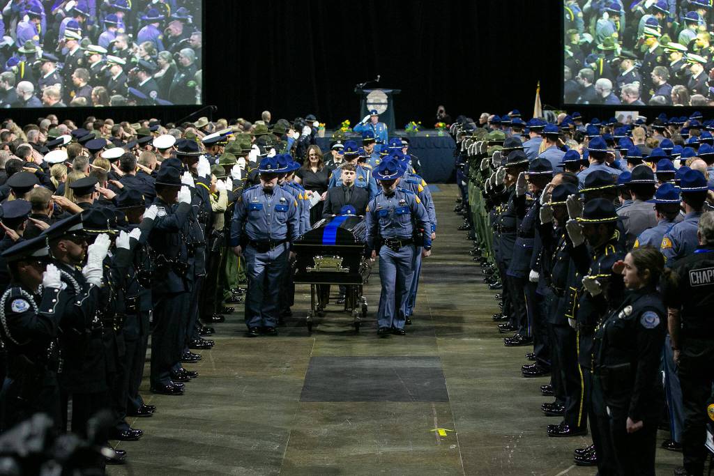 Washington State Trooper Chris Gadd is brought out by fellow troopers following a memorial ceremony on Tuesday, March 12, 2024, at Angel of the Winds Arena in Everett, Washington. (Ryan Berry / The Herald)