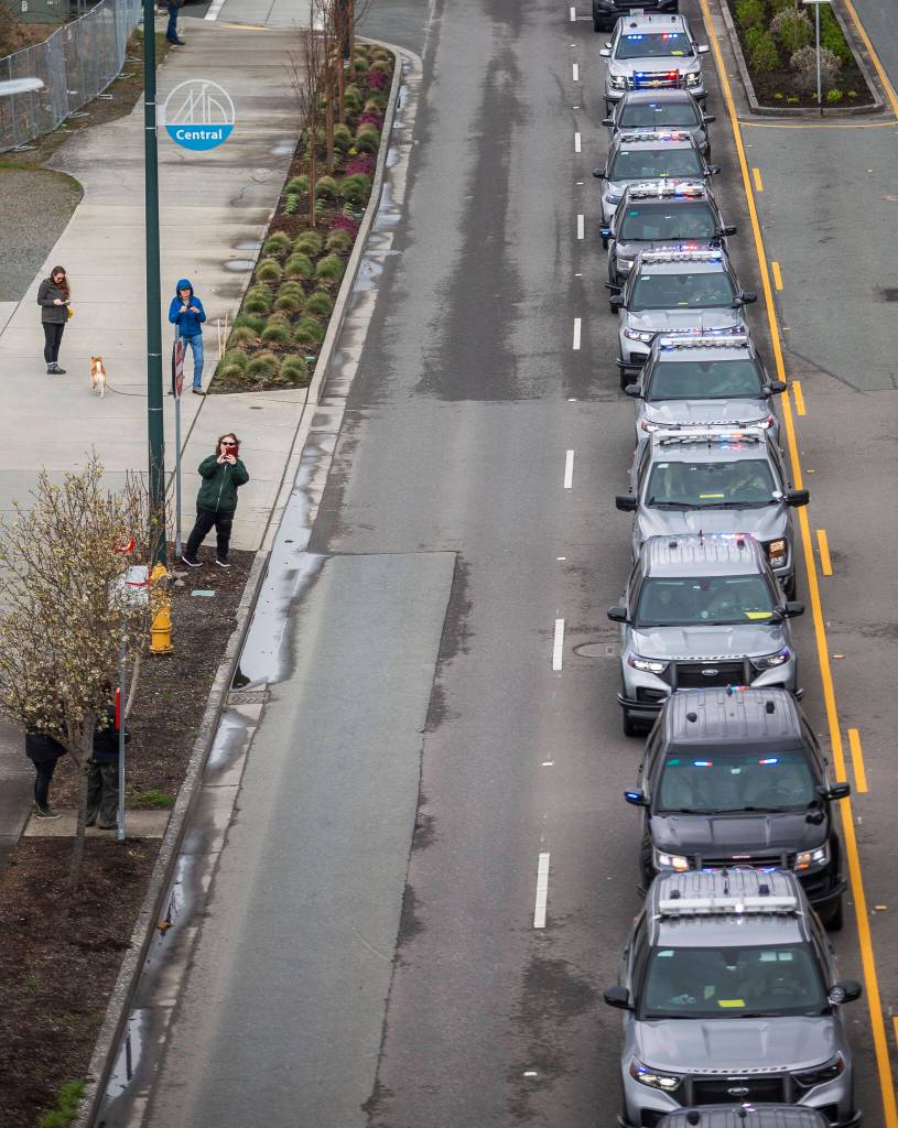 Police cars stop along Marine View Drive during a memorial procession for Washington State Trooper Christopher Gadd on Tuesday, March 12, 2024 in Everett, Washington. (Olivia Vanni / The Herald)