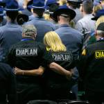 Chaplains and other members of the crowd listen as Taps is played during a memorial for Washington State Trooper Chris Gadd on Tuesday, March 12, 2024, at Angel of the Winds Arena in Everett, Washington. (Ryan Berry / The Herald)