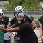 Kentwood assistant coach works with defensive linemen during practice.