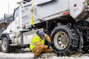 A city of Kent Public Works crew member chains up a truck Feb. 3 to help clear snow from streets. COURTESY PHOTO, City of Kent