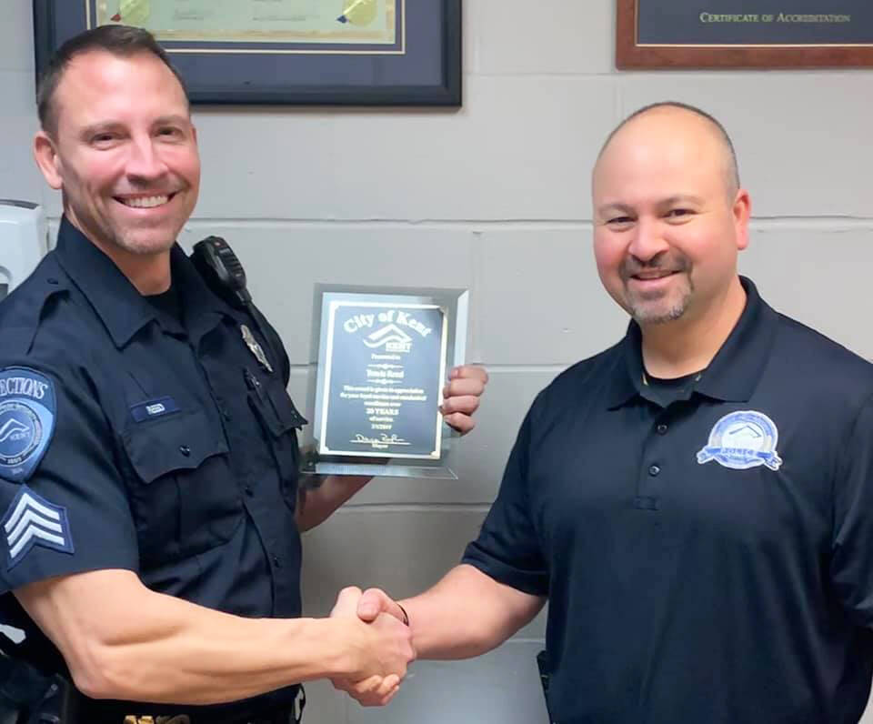 City of Kent Corrections Officer Travis Reed, left, receives recognition in 2019 for 20 years on the job from Police Chief Rafael Padilla. Reed is on administrative leave, under investigation for alleged misconduct while on duty. FILE PHOTO, City of Kent