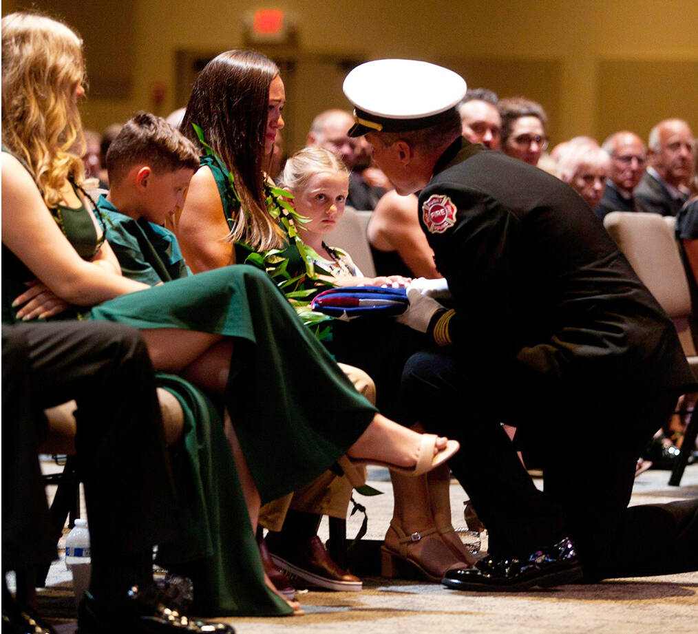 A fire official presents a folded American flag to Abby Minneman, the wife of Capt. Brandon Minneman, on July 18 at a Celebration of Life service at New Life Church in Renton. COURTESY PHOTO, Puget Sound Fire