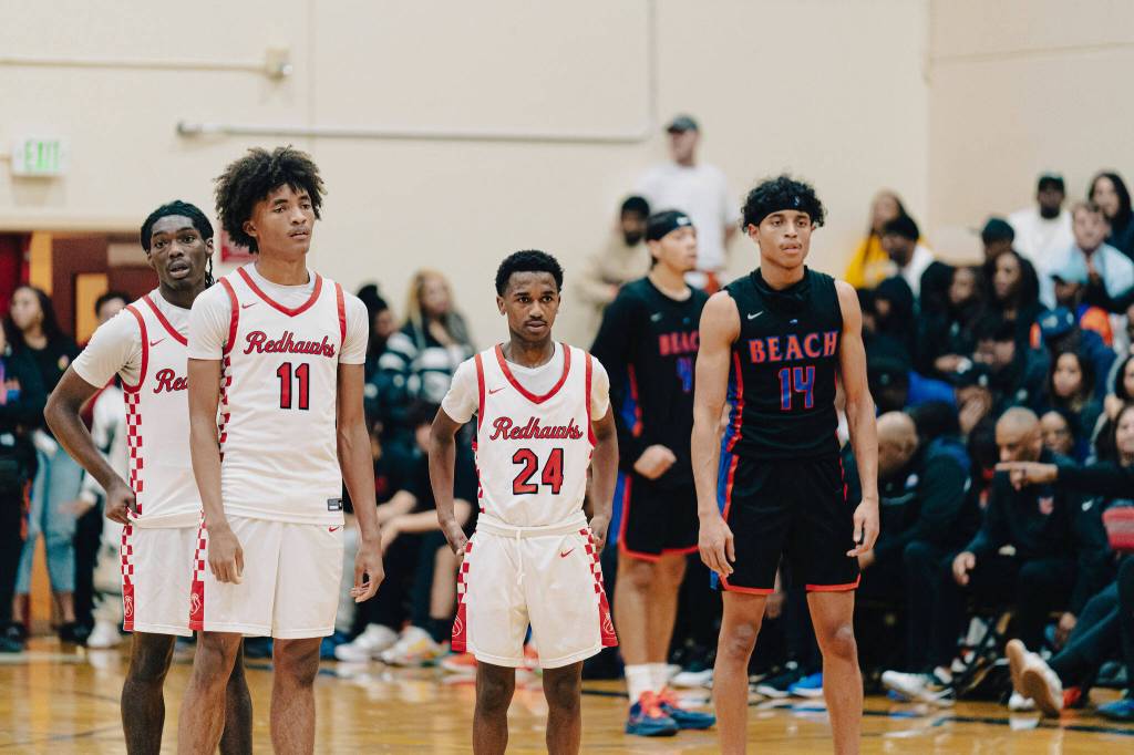 Nate Omar (background) stands with Juice White-Kelley (11) and Adan Abdi (24) during free throws. Photo by VonRico ONeal /@Ricosuavej
