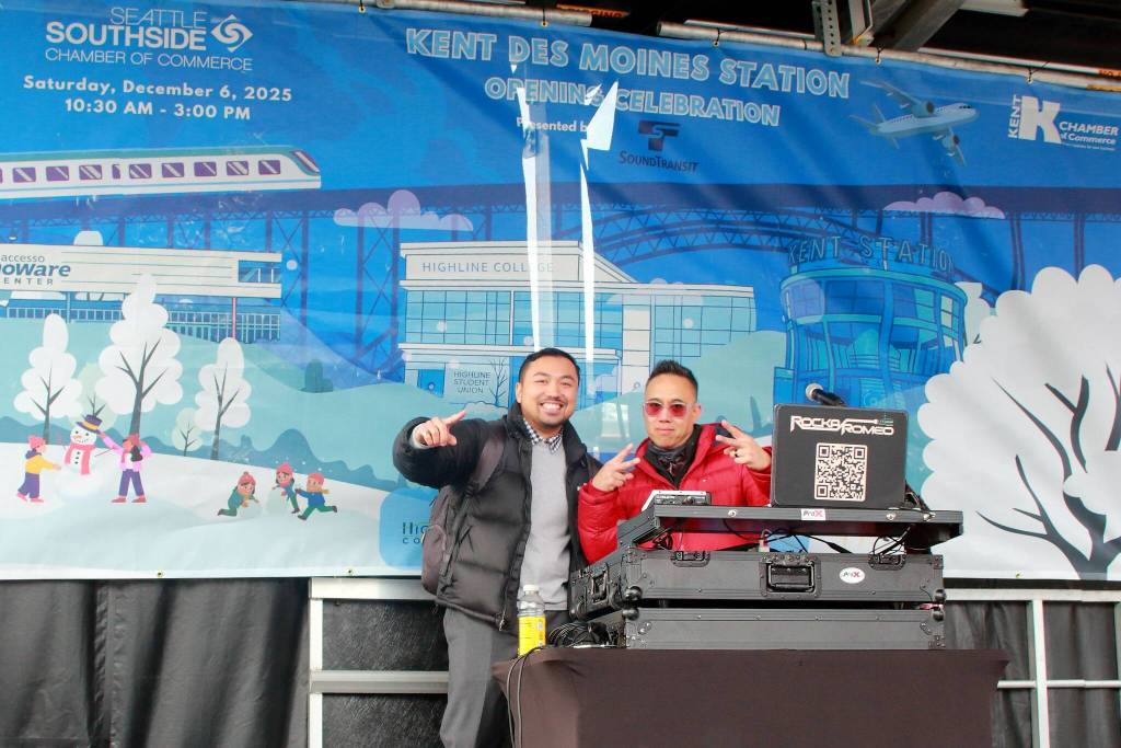 DJs pose in front of a celebratory banner at the new Kent-Des Moines light rail station on Dec. 6. Photo by Keelin Everly-Lang / Sound Publishing