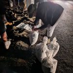 Taken at 5:16 p.m. on Thursday night, Maplewood neighbors work into the night to create sandbags to keep the Cedar River from flooding homes. The neighbors had paid Burien Bark to deliver the sand, which they hand-bagged. Photo by Bailey Jo Josie/Sound Publishing.