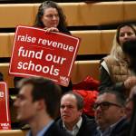 An attendee displays a sign at the School Funding Crisis regional town hall on Jan. 7 at Newport High School in Bellevue. Andy Nystrom/ staff photo