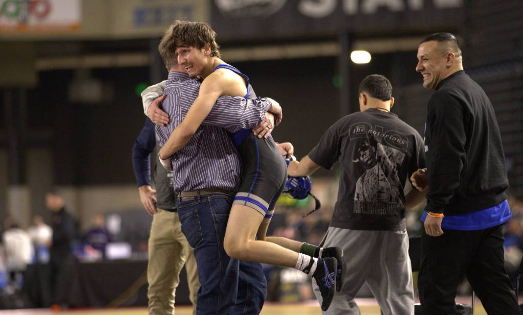 Farzad Karimi leaps into the arms of head coach Todd Owens. Ben Ray / The Reporter